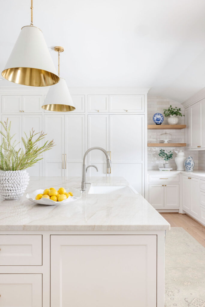 The kitchen, too, underwent a huge metamorphosis. They stripped away the dated cabinetry and replaced it with custom-built, soft neutral cabinets that offered both elegance and practicality. A spacious island became the heart of the kitchen, with a stunning slab of Taj Mahal quartzite that is truly a stunner. The subtle blend of countertops, textured backsplash and brass fixtures lent an air of sophistication without overwhelming the space.